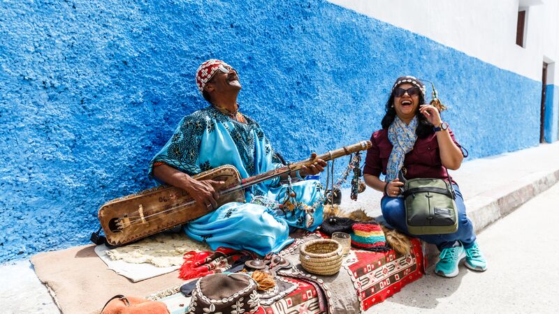 A traveller laughing with a local musician in Rabat, Morocco