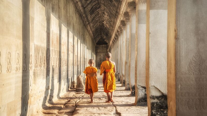 Two monks walking through the grounds of Angkor Wat in Cambodia