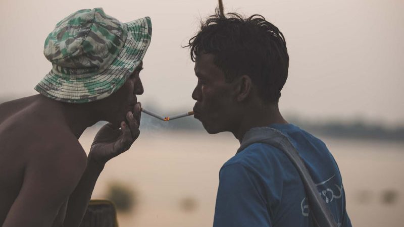 Locals in Myanmar fishing vallage lighting cigarettes