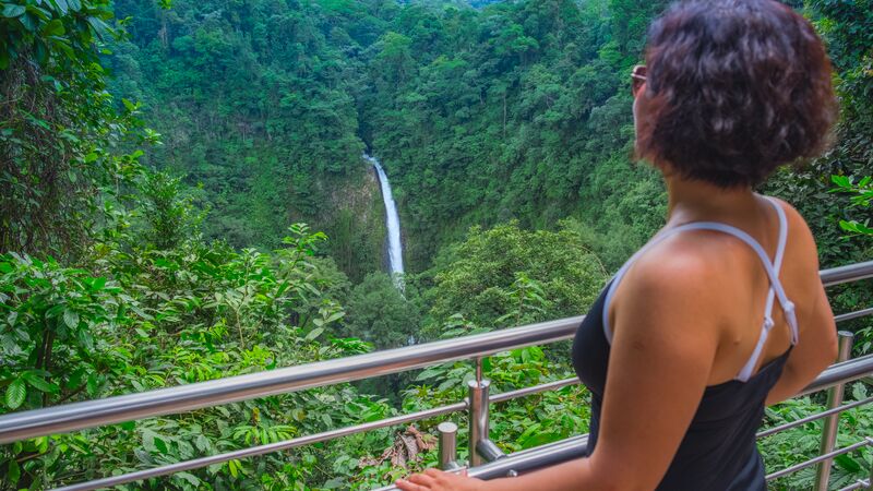 Woman looking out over a jungle and waterfall