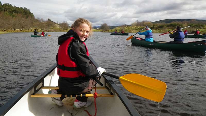 Family canoeing on Caledonian Canal in Scotland 