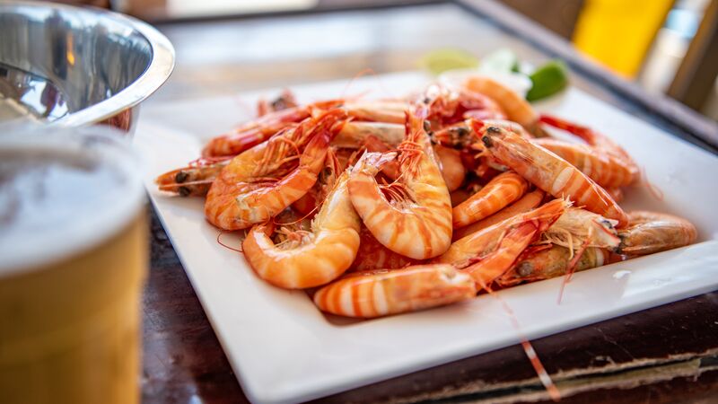 A plate of fresh prawns sitting beside a cold beer.