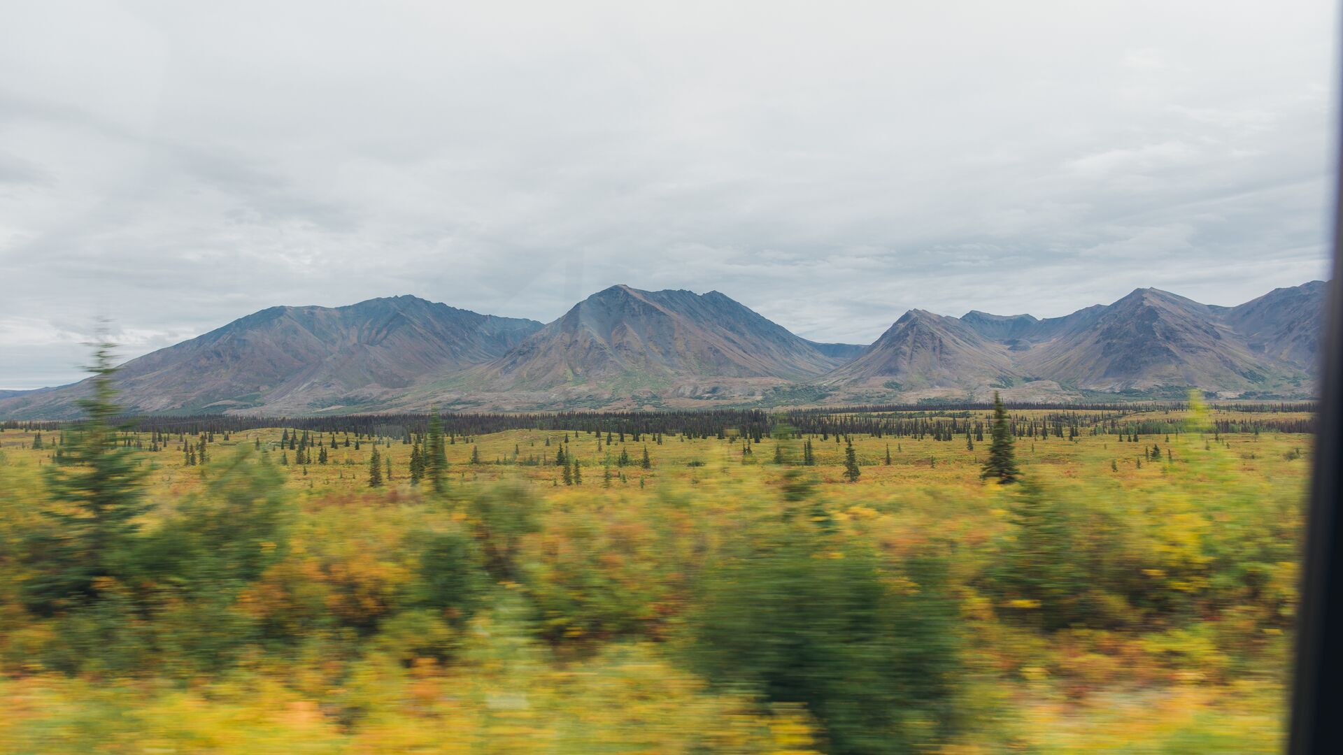 Mountain scenery blurring by outside of a car window.