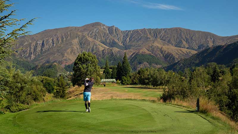 A man taking a swing at the Arrowtown Golf Course in Arrowtown, Queenstown.