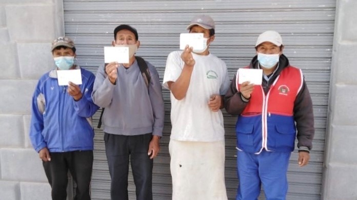 Porters in Peru holding their vaccination forms