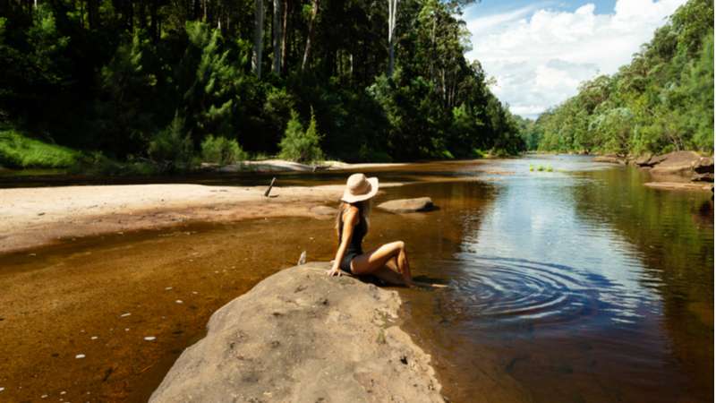 Woman sits on a rock in the middle of the Grose River in the Blue Mountains, New South Wales. 