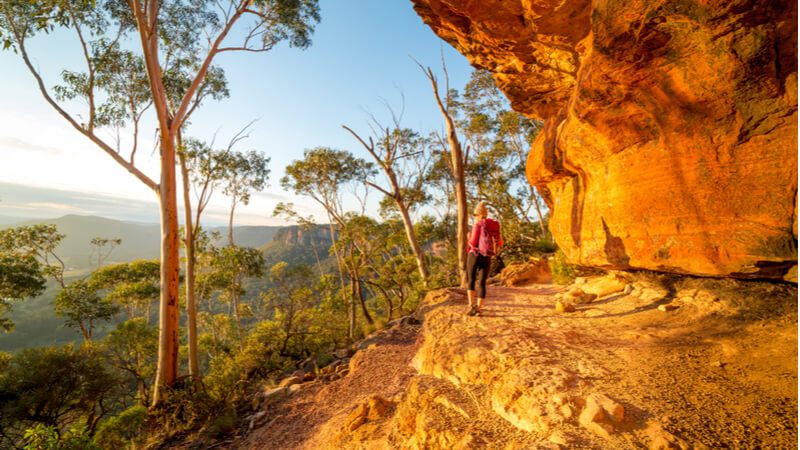 The sun sets on a hiker following the Valley of the Waters walk past sandstone cliffs in the Blue Mountains, New South Wales.