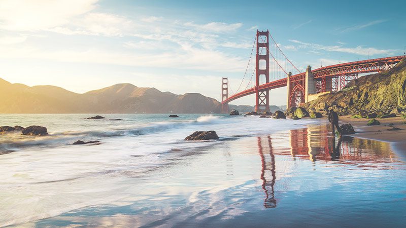 The beach in San Francisco with a view of the Golden Gate Bridge.