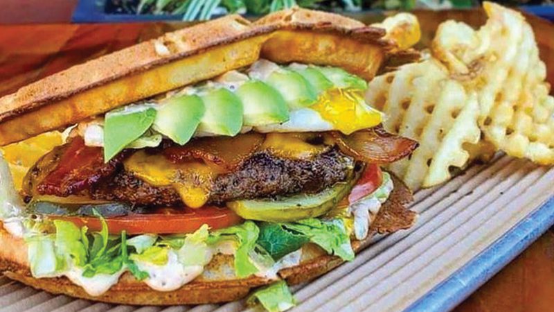 A fried chicken waffle sandwich with waffle fries on the side from Bruxie in Santa Monica.