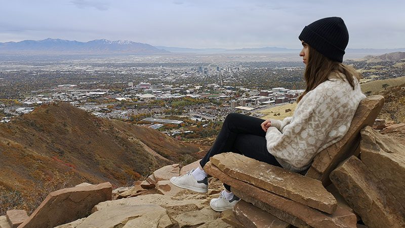 A woman sitting in a seat-like rock formation at the top of the Living Room Hike in Salt Lake City. 