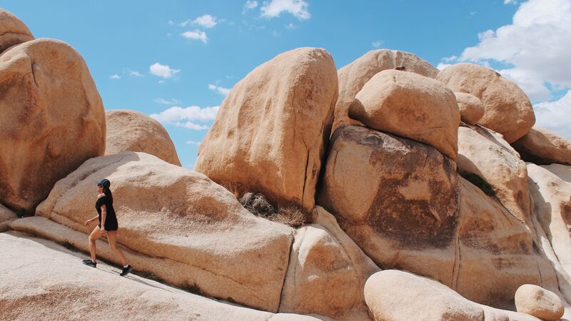 A woman walking up a rock formation in Joshua Tree National Park, California.