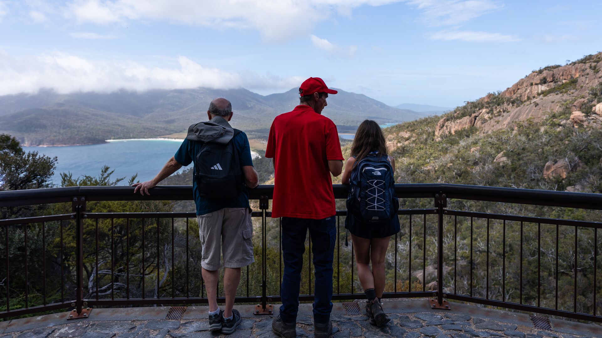 An Intrepid leader and two travellers stand at a lookout in Freycinet National Park