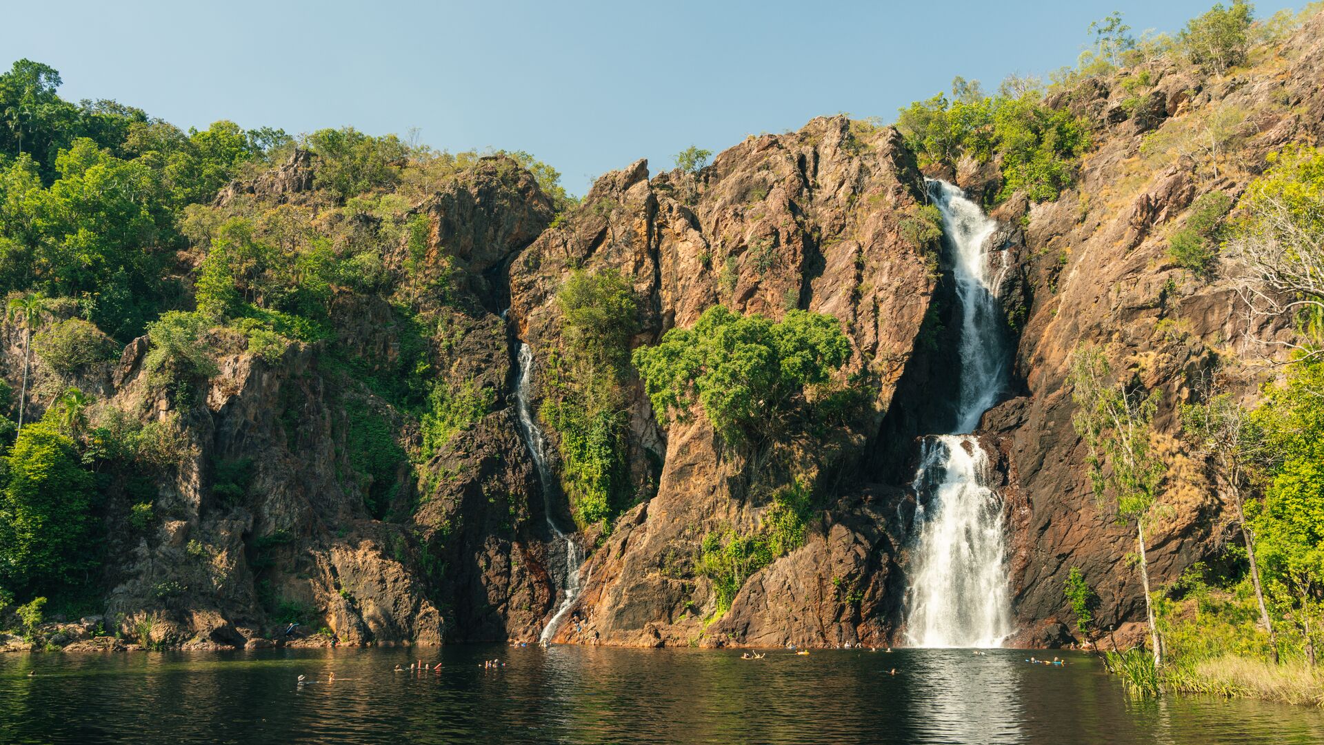 Wangi Falls in Litchfield National Park with swimmers in water and rushing waterfall.