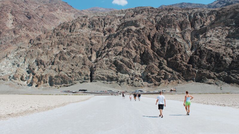 A group of travelers walking towards a rocky cliff face in Death Valley National Park. 