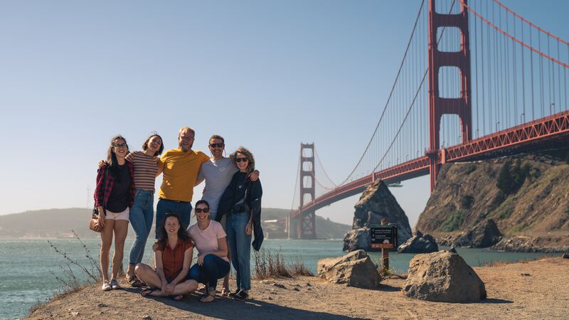 A group of travelers standing in front of the Golden Gate Bridge in San Francisco.
