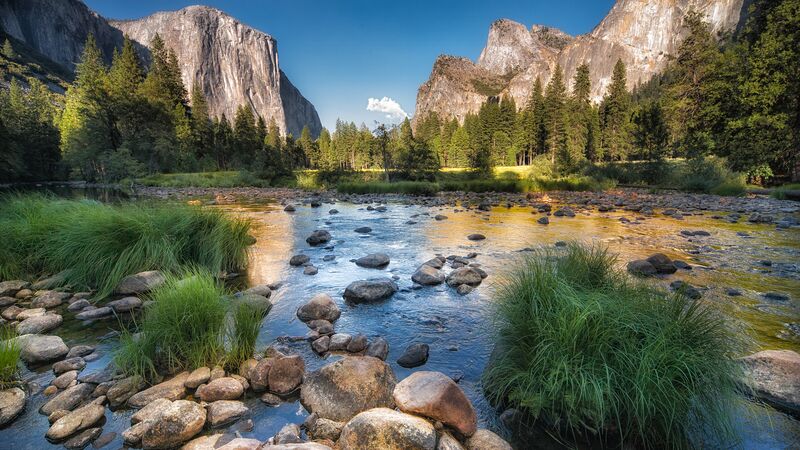 A peaceful river with rocky mountains in the background at Yosemite National Park. 