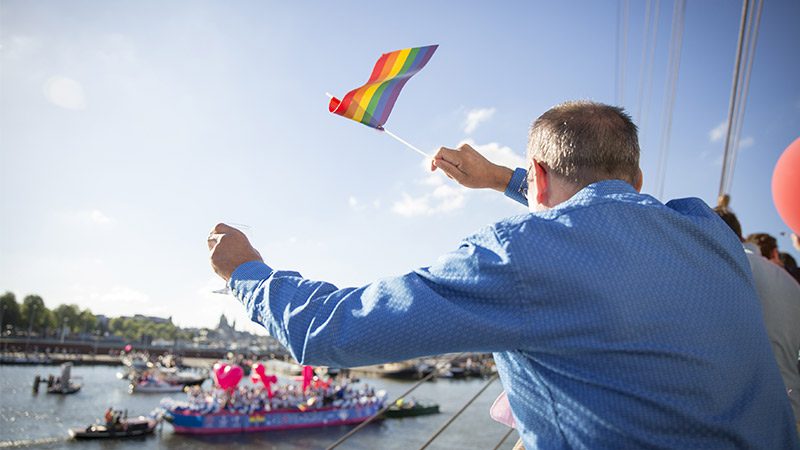 People waving flags at the Amsterdam Canal Pride Parade