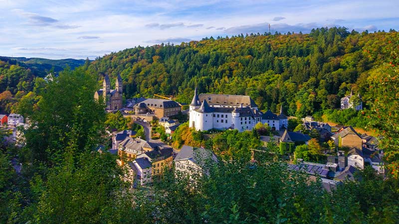 An aerial view of Clervaux, a small city in Luxembourg, nestled in lush forested woodland.