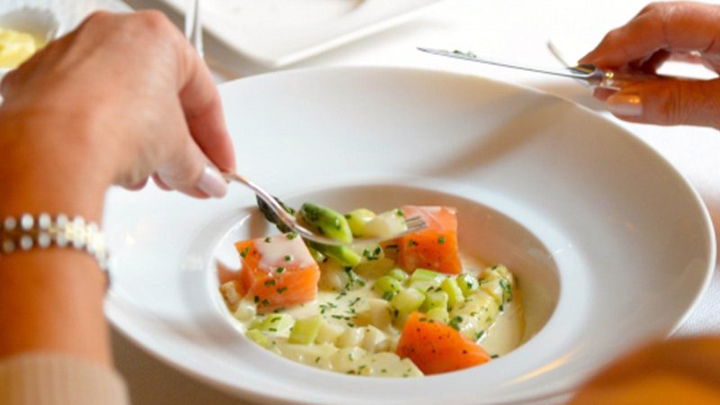 Woman eating a salmon and vegetable dish from Le Bouquet Garni in Luxembourg.
