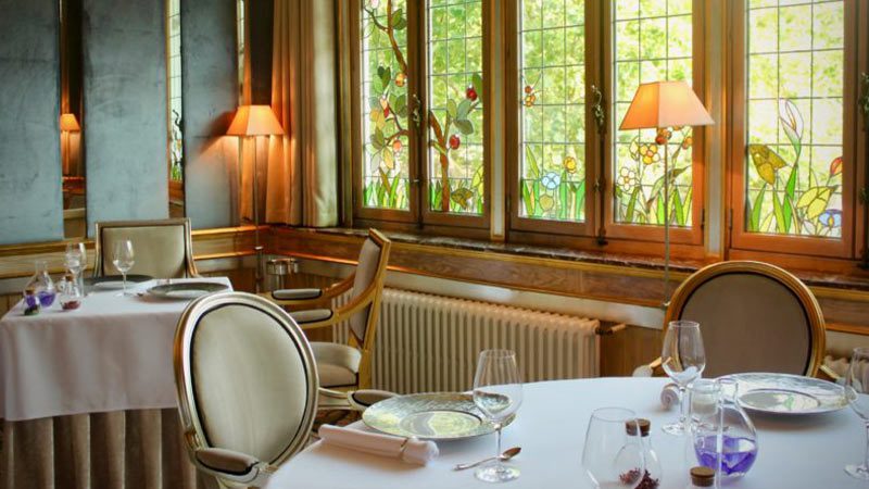 The opulent interior of La Cristallerie with perfectly poised place settings sitting atop crisp, white tablecloths.