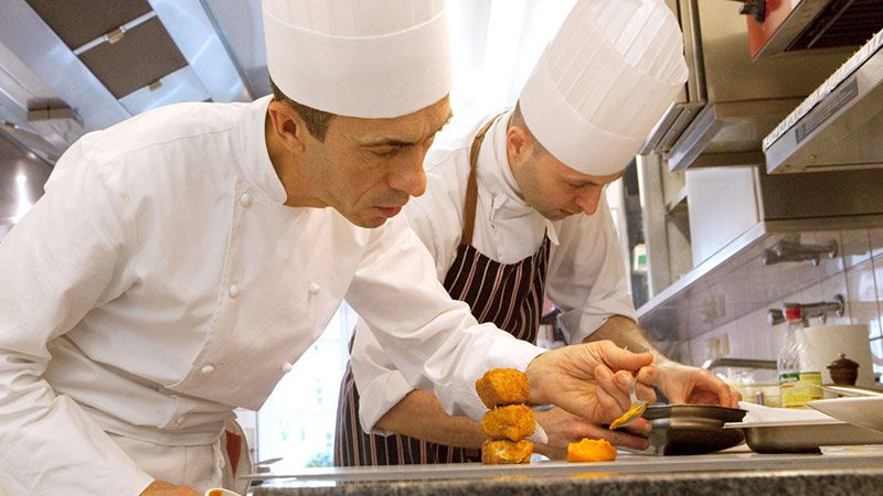 Two chefs plating up dishes in the kitchen at Mosconi.