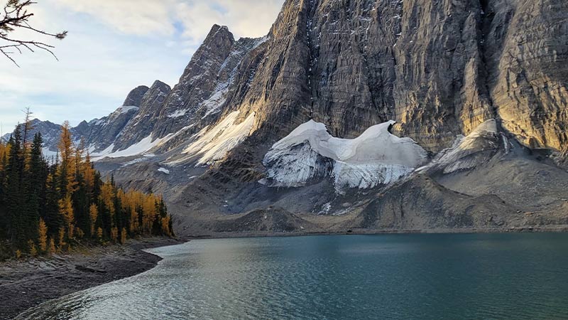 The blue/green Floe Lake sitting at the base of rocky mountains in the Canadian Rockies.