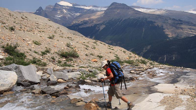 Traveller hiking across a rocky water path along the Iceline Trail.