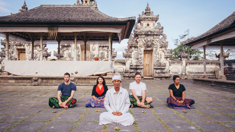Travellers meditating at a temple in Bali