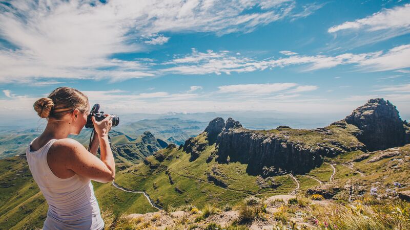 A woman photographing the view of the Drakensberg in South Africa 