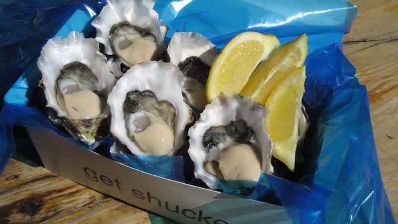 Freshly shucked oysters for take away served with a few lemon wedges.