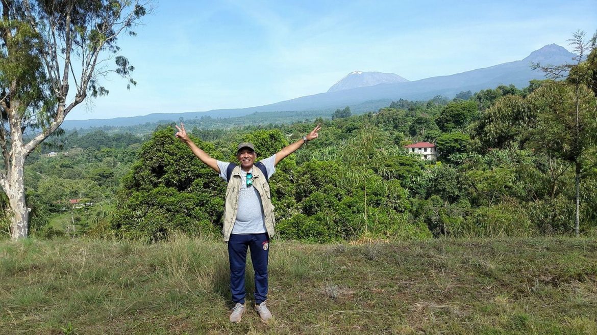 A happy man stands with his arms up