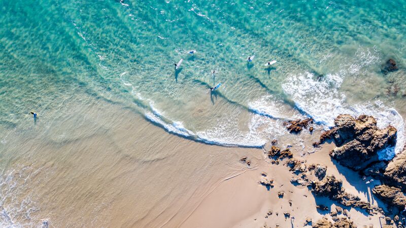 A bunch of people surfing in the gently waters of Byron Bay.