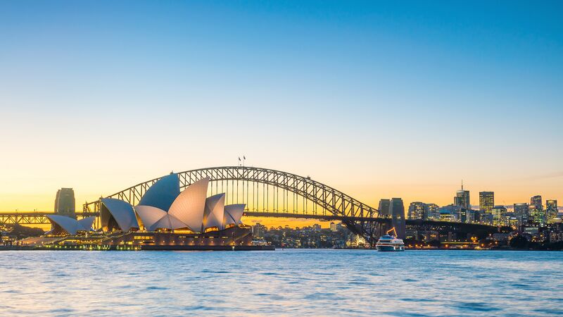 The Sydney Opera House and Harbour Bridge against a setting sun.