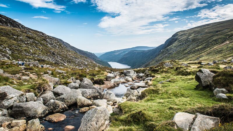 Craggy rocks sitting beside a stream of water down a green hill in the Wicklow mountains