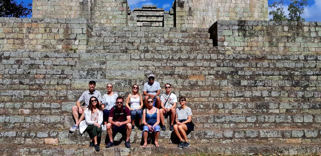 A group of people sitting on stone steps at a ruin in Honduras