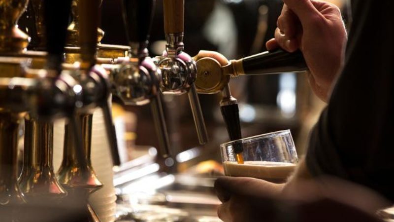A bartender pouring a frothy pint of Guinness.