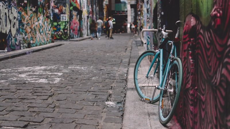 A group of people looking at graffiti down a street in Melbourne. 