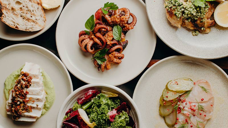 A flat lay of several colourful dishes including octopus.