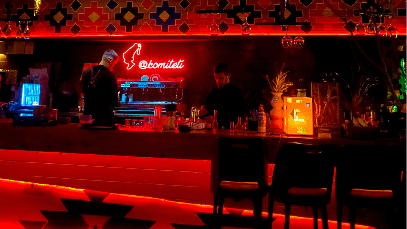 A red-lit bar with a neon sign above the bar