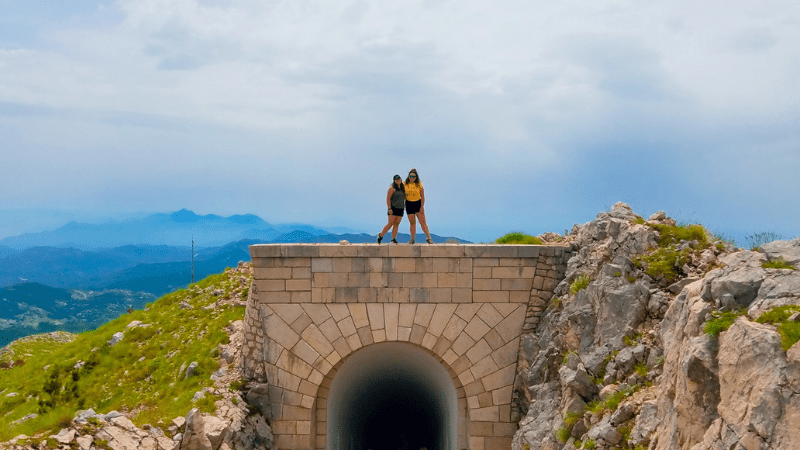 Two women standing on top of a bridge