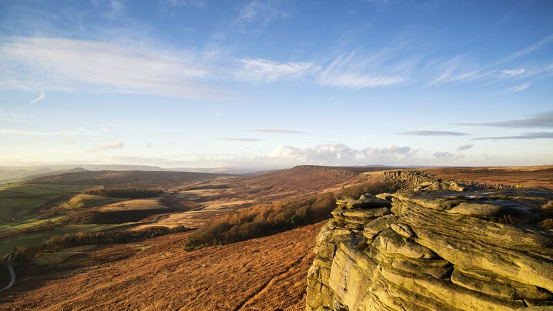 The stunning landscape of Stanage Edge in the Peak District under a clear, blue sky.