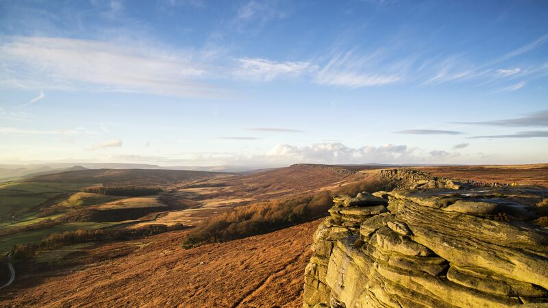 The stunning landscape of Stanage Edge in the Peak District under a clear, blue sky. 