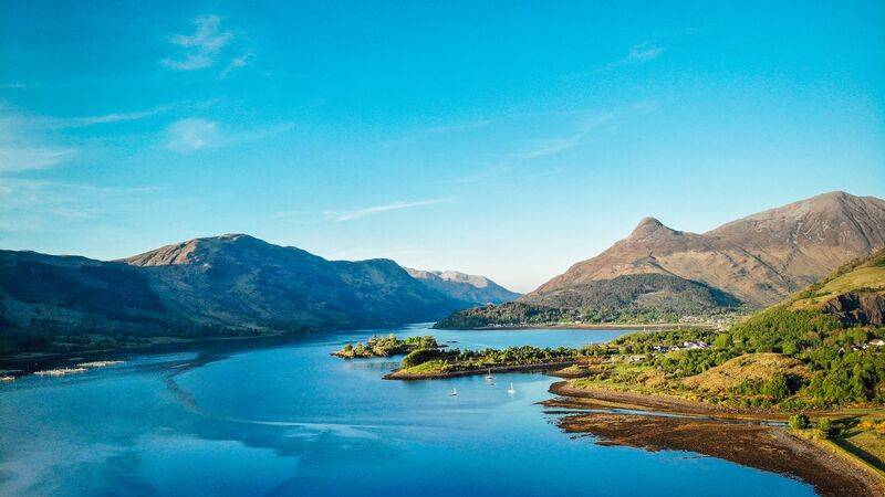An aerial view of Loch Leven in Glencoe with surrounding mountain ranges in the background.