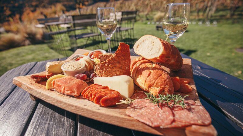 Cheese and meat platter served alongside glasses of wine.