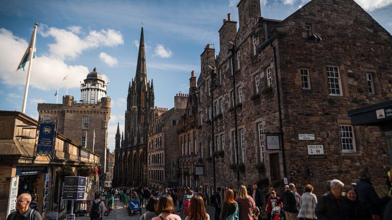 A bustling Edinburgh street lined with ancient brick buildings. 