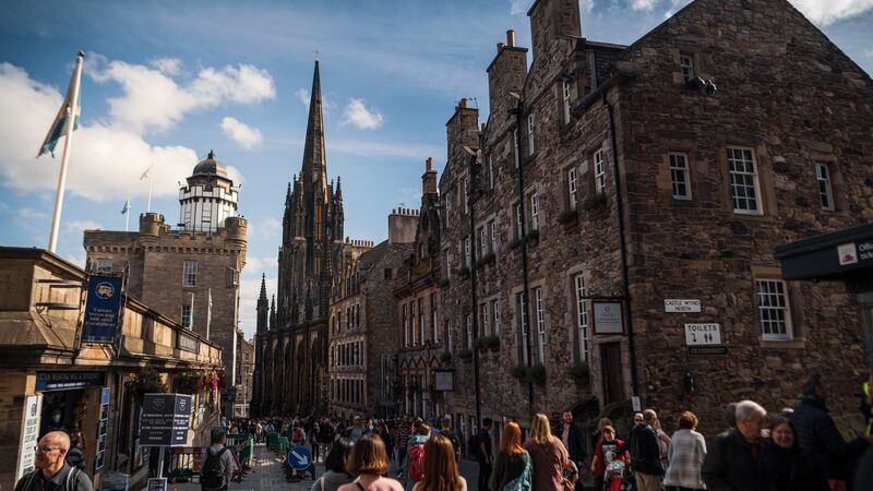 A bustling Edinburgh street lined with ancient brick buildings.