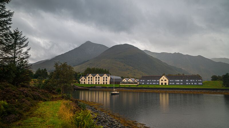 The loch at Glen Coe with mountain ranges in the distance on an overcast, gloomy day.