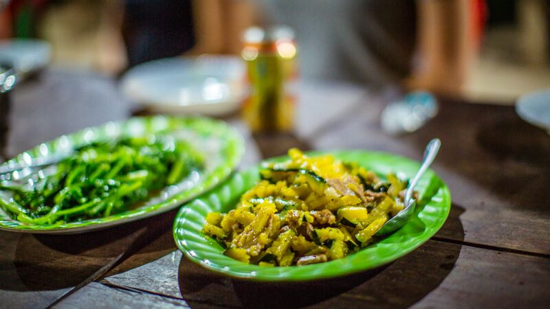 Two plates piled high with traditional Cambodian food. 