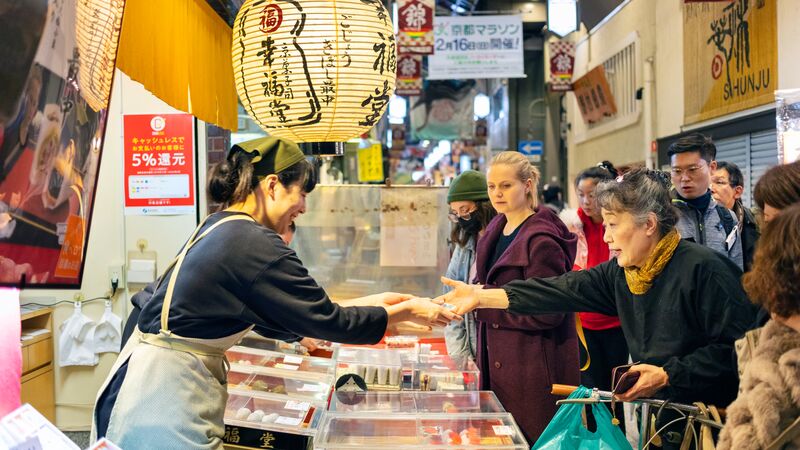 A group of shoppers at a food stall in a Japanese market