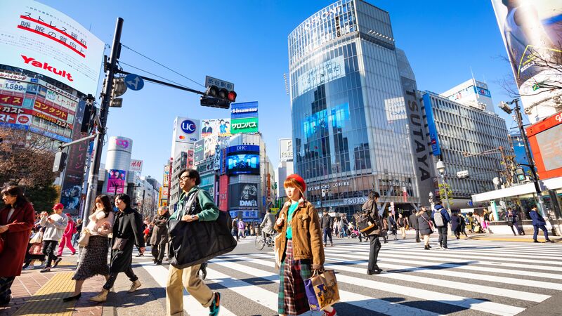 People walking in every direction across Shibuya crossing.